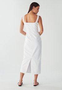 Biele, bezrukávové midi šaty so štvorcovým chrbtom, priliehavý strih a stredný rozparok. Hladká tkanina s skrytom zapínaním na zips v zadnej časti.