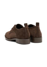 Pantofi din suede maro cu o textură netedă, vârf rotunjit și toc joasă, ribatată, de culoare maro. Prezintă cusături contrastante și un dispozitiv de prindere pe toc.