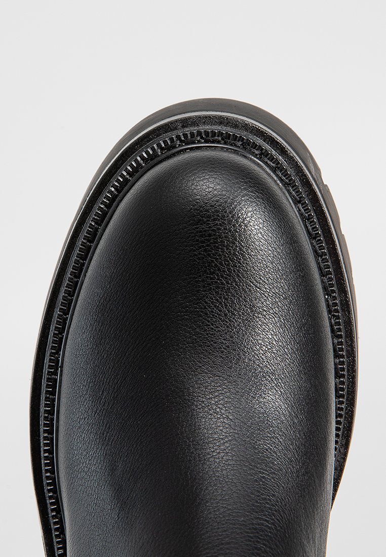Schwarzer Lederschuh mit glatter Textur, runder Zehenform und dekorativen Nähten entlang der Kante der Sohle. Minimalistisches Design.