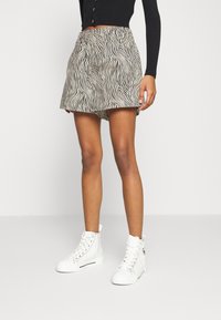 Pantalones cortos de estampado de cebra hechos de tela ligera con una cintura elástica. Combinados con zapatillas altas blancas.