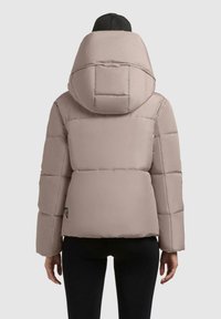 Pufferjakke i lys beige med en stor hætte, quiltet design og en cropped silhuet. Synlig mærkeetiket på den nederste venstre side.