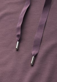 Fialová mikina vyrobená z tkaniny s texturovaným povrchem. Má dvě odpovídající stahovací šňůrky se stříbrnými kovovými koncovkami. Jednoduchý, funkční design.