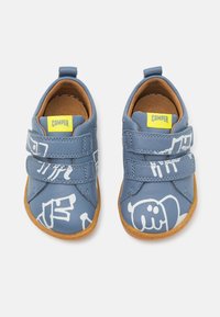 Niebieskie skórzane buty z dwoma rzepami, zdobione białymi grafikami w stylu kreskówkowym i brązową gumową podeszwą. Wyłożone jasnobrązowym materiałem.