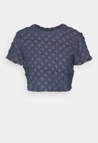 Avkortet marineblå topp med en teksturert, diamantmønstret design og korte ermer. Laget av et lett, vevd stoff.
