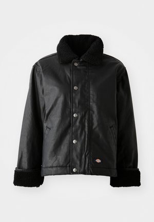 Veste en cuir noir avec col en peau de mouton, fermeture à bouton-pression, poches latérales et poignets en tissu doux. Comprend un patch avec le logo de la marque.
