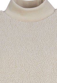 Haut en polar couleur crème avec une surface texturée et un col haut en côtes. Le tissu semble doux et chaud, avec un design uni.