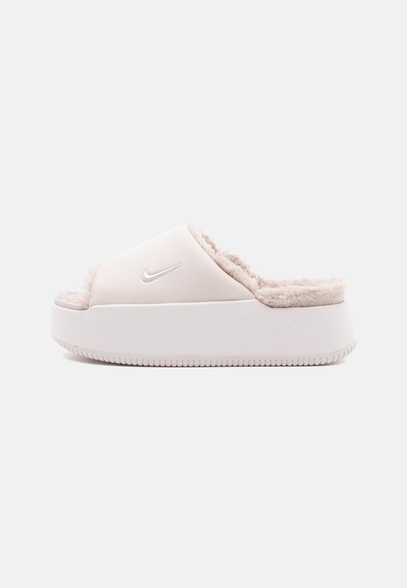 Sandalia tipo slide de Nike en rosa claro, con un forro de pelo suave, material superior liso y una suela blanca gruesa con un fondo texturizado.