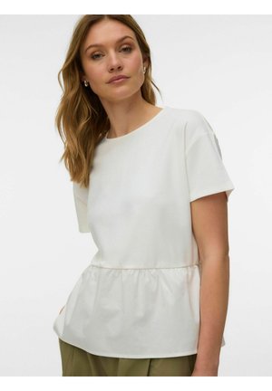 Kobieta o jasnobrązowych włosach, nosząca srebrne kolczyki koła i białą bluzkę z krótkim rękawem typu peplum, stojąca na jednolitym tle.