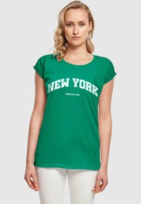 Grøn bomulds t-shirt med korte rullede ærmer og rund halsudskæring, med "NEW YORK" trykt i fede hvide bogstaver på forsiden.