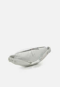 Ljusgrå midjeväska i hållbart material, med dragkedjestängning, justerbar rem och en strömlinjeformad, oval form.