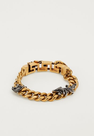 Armbanduhr mit vergoldetem Kettendesign, das aus miteinander verbundenen Gliedern besteht. Akzentuiert mit schwarzen Metall-Details und einem dekorativen Motiv, entworfen für einen mutigen Look.