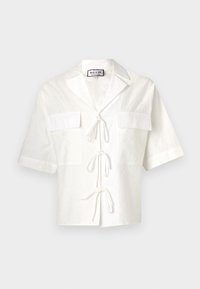 Witte shirt met korte mouwen en een kraag, voorzien van twee voorzakken en een striksluiting in het midden. Geweven stof met een subtiel patroon.