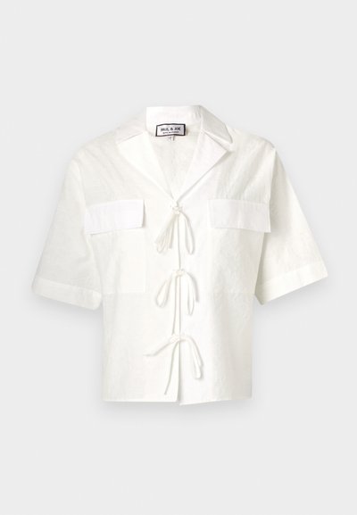 Weißes kurzärmliges Hemd mit Kragen, ausgestattet mit zwei Fronttaschen und einer Bindung in der Mitte. Texturiertes Gewebe mit einem subtilen Muster.