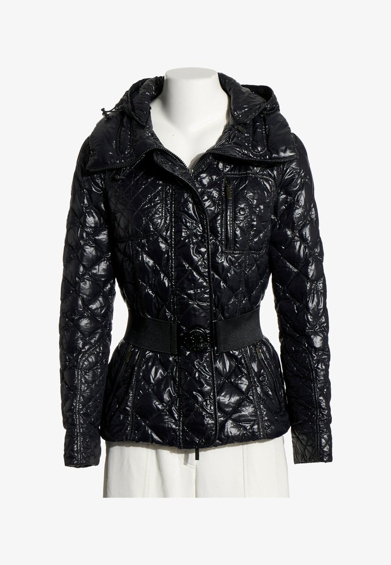 Veste matelassée noire brillante avec ceinture à la taille, fermeture éclair frontale, poche poitrine zippée et capuche sur un buste de mannequin blanc.