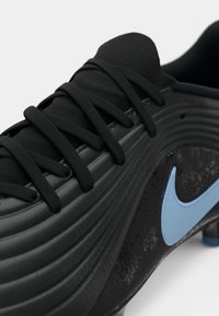 Μαύρο ποδοσφαιρικό παπούτσι με υφή στην επιφάνεια, κομψό σχέδιο και μπλε λογότυπο Nike. Διαθέτει αντίθετα υλικά και ενσωματωμένα κορδόνια για ασφαλή εφαρμογή.