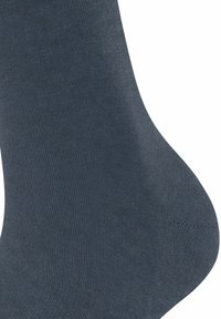 Chaussette bleu foncé avec un tissu lisse et texturé. Le design est simple, présentant une forme de pied typique et une couleur uniforme sur toute la surface.