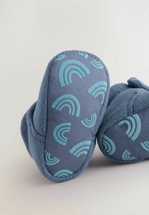Blaue Hausschuhe aus einem strukturierten Stoff mit einem Muster aus türkisfarbenen Regenbögen. Weiche Fleece-Fütterung und gepolstertes Design für zusätzlichen Komfort.