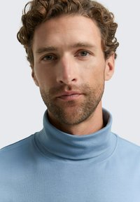 Hellblauer Rollkragenpullover aus weichem, elastischem Stoff mit glatter Textur. Verfügt über einen hohen Kragen und ein minimalistisches Design.