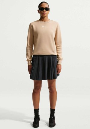 Sudadera beige de manga larga con el logo de Nike en blanco; falda negra plisada; zapatillas y calcetines negros. Diseño minimalista, estilo casual.