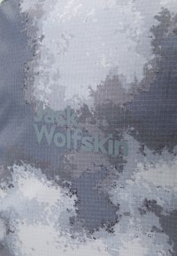 Tejido gris con un patrón de nubes pixeladas; presenta el logotipo de "Jack Wolfskin" en gris claro, superficie texturizada y diseño de tejido en forma de cuadrícula.