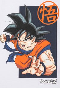 T-shirt blanc pour homme avec un graphique d'un personnage aux cheveux noirs en épis, portant une tenue orange avec des accents bleus et une main tendue.