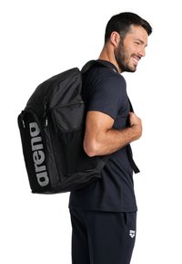 Sac à dos noir avec plusieurs poches zippées, accents en mesh et logo bien visible. Forme rectangulaire avec des bretelles rembourrées pour le confort.