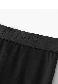 Schwarzer Stretchstoff mit glatter Textur, ausgestattet mit einem gewebten Bund, auf dem "FINN" in passender schwarzer Schrift geprägt ist.