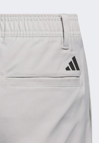 Lichtgrijze sportshorts met een elastische tailleband, voorzien van een zwart Adidas-logo en een horizontale zak aan de zijkant.