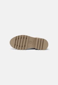 Semelle de chaussure beige avec des rainures horizontales profondes et un logo de marque au centre, taille 37, présentée sur un fond blanc.