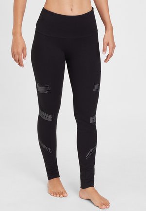 Black leggings with a high waistband, featuring reflective stripe patterns on the sides. Made from stretchable material, smooth texture.
