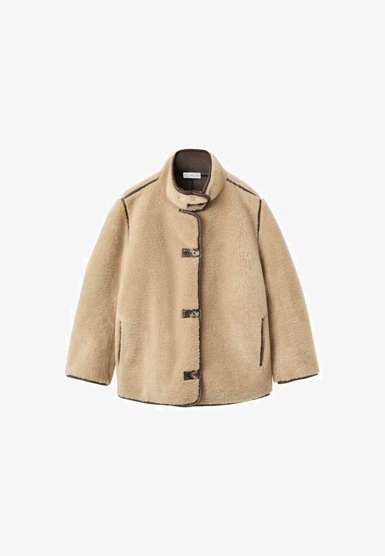 Beige shearlingjacka med hög krage, knappstängning, framfickor och kontrasterande mörk söm. Mjuk textur med en avslappnad design.