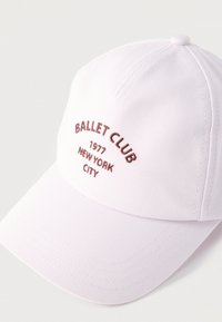Λευκό καπέλο μπέιζμπολ με κεντημένο μπορντό κείμενο "BALLET CLUB 1977 NEW YORK CITY" στην μπροστινή επιφάνεια.