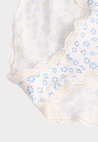 Tela de algodón con estampado floral que presenta flores azules sobre un fondo blanco, rematada con un delicado borde de encaje con forma de concha.
