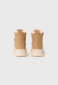 Stivaletti alla caviglia in suede color tan con un morbido rivestimento bianco, dotati di una suola spessa color crema e di un bordo per il tallone ad anello per una facile calzata.