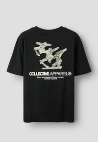 Svart bomulls-T-skjorte med et kamuflasjemønster på baksiden og hvit tekst under. Kortermet med rund hals.