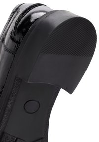 Scarpa in pelle nera lucida con una suola in gomma spessa e testurizzata. Presenta una punta arrotondata e un sottile dettaglio di cucitura sulla tomaia.