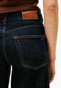 Donker denim jeans hebben een rechte snit, platte achterzakken, contraststiksels en een bruine leren logo-label op de tailleband.