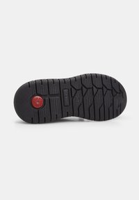 Talpa de cauciuc negru cu un model texturat de crampoane. Are un logo circular roșu și un branding modelat pe suprafață.