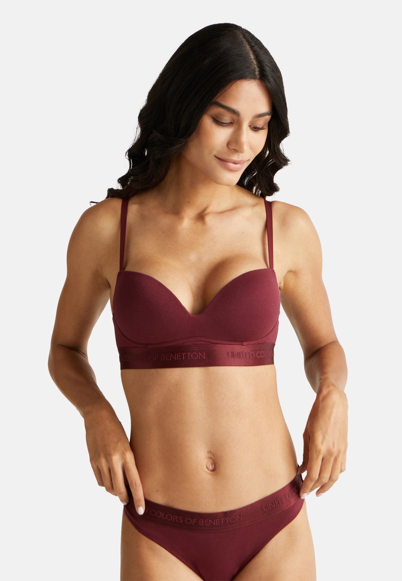 Bordeauxkleurige bh met zachte cups, dunne verstelbare bandjes en een elastische band met het merk "United Colors of Benetton".