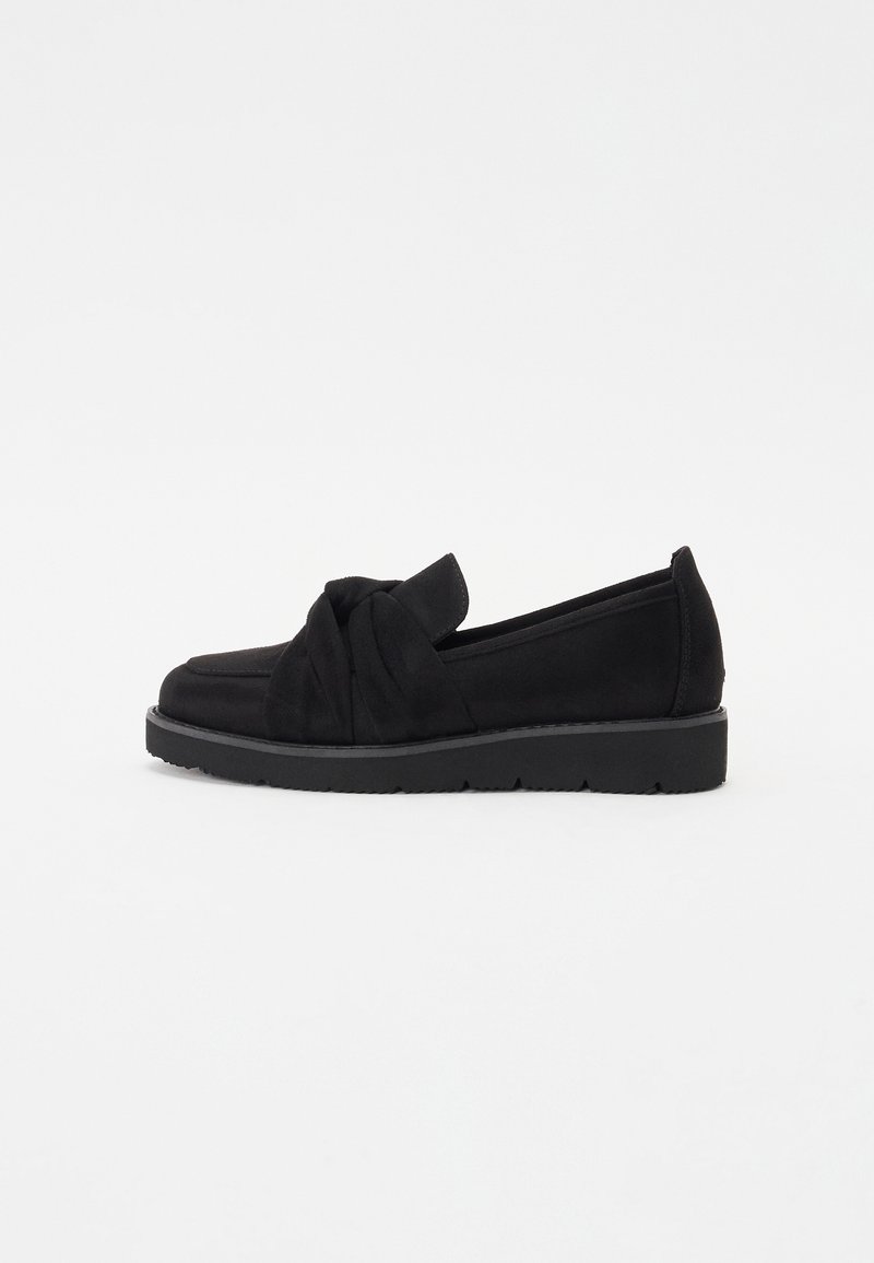 Fekete velúr slip-on cipők, a felsőrészen csomózott dizájnnal és textúrázott gumitalppal. Alacsony profilú sziluett és minimalista részletezés.