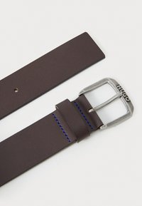 Brown leather belt with a silver metal buckle, featuring blue stitching detail and a branded logo. Smooth texture, rectangular shape.