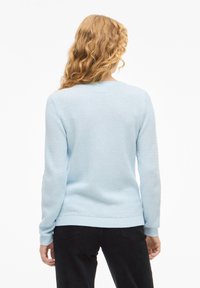 Ανοιχτογάλαζο πλεκτό πουλόβερ με υφή σχεδίου, ριμπ μανσέτες και τελείωμα. Η πίσω όψη δείχνει στρογγυλή λαιμόκοψη και απλή σιλουέτα.