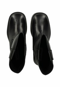 Botines de cuero negro con un acabado suave, puntera redondeada y pestañas laterales para facilitar su uso. Detalles cosidos a lo largo de la suela.