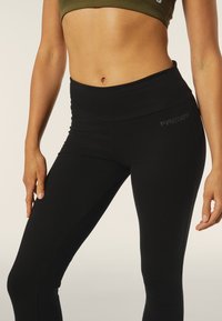 Leggings neri con una cintura ampia, realizzati in materiale elasticizzato. Presentano un discreto logo "FREDDY" sull'anca. Texture liscia.