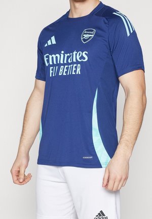 Maillot de sport bleu marine avec des accents bleu clair. Porte le logo "Emirates Fly Better" et le blason d'Arsenal. Fabriqué en matériau respirant, Aeroready.