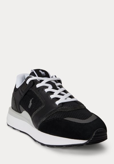 Ασπρόμαυρο αθλητικό παπούτσι με πάνελ από δίχτυ και σουέντ, λευκά κορδόνια, μαξιλαρωμένο περιλαίμιο αστραγάλου και λογότυπο Polo στο πλάι και στη γλώσσα.