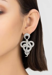 Sparkling silver chandelier earrings feature intricate intertwined design, adorned with small clear rhinestones, showcasing a shiny texture.