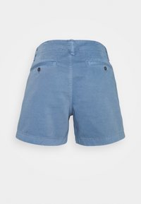 Blå bomullsshorts med en slät yta, som har ett midjeband, två bakfickor med svarta knappar och uppvikt kant.