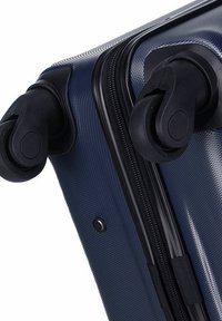 Marineblaue Hartschalentasche mit strukturierter Oberfläche, schwarzem Reißverschluss und doppelten multidirektionalen Rollen für einfache Mobilität.