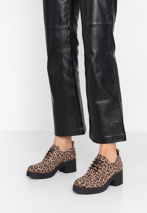 Lepardo-print enkelschoenen met een ronde neus, zwarte zool en blokhak, gecombineerd met zwarte faux leren broek.